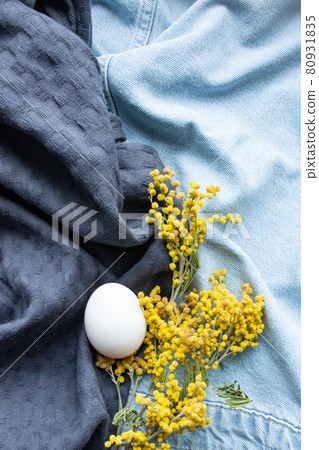 egg and mimosa lay on a blue fabric background 80931835