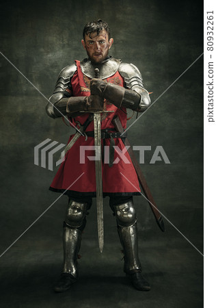 Portrait of one brutal bearded man, medeival warrior or knight with dirty wounded face holding sword 80932261