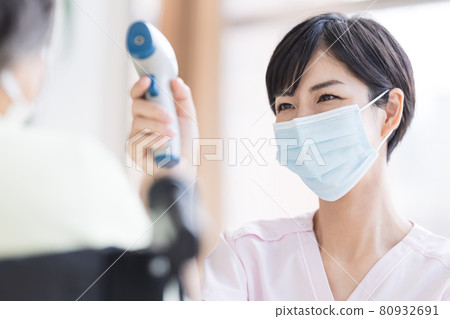 Nursing care image Medical worker who measures the temperature with a non-contact thermometer Nursing care image Medical worker who measures the temperature with a non-contact thermometer 80932691