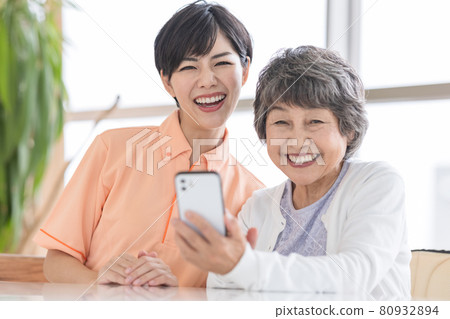 Nursing image portrait of a senior woman and a caregiver looking at a smartphone 80932894