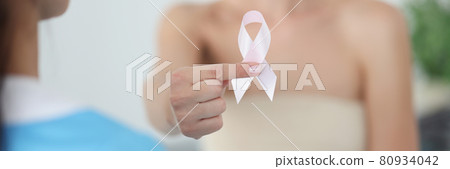 Woman with bandaged chest holding pink ribbon at doctor appointment closeup 80934042
