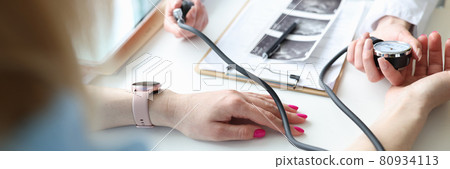 Gynecologist doctor measuring blood pressure of young pregnant woman in clinic closeup 80934113