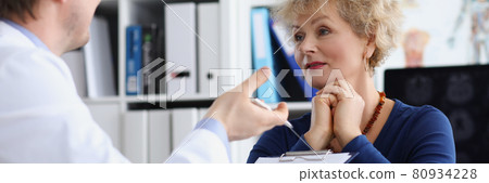 Elderly woman sitting at table at doctor appointment in clinic 80934228