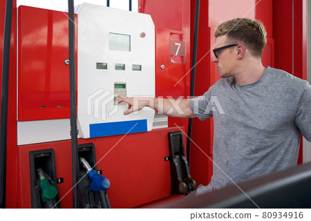 Young caucasian driver with sunglass, pressing the number on refueling machine of gas stations to refuel pickup truck. 80934916