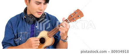 Young asian man with headphones playing an Ukulele guitar. Portrait on white background with studio light. Close Up 80934918