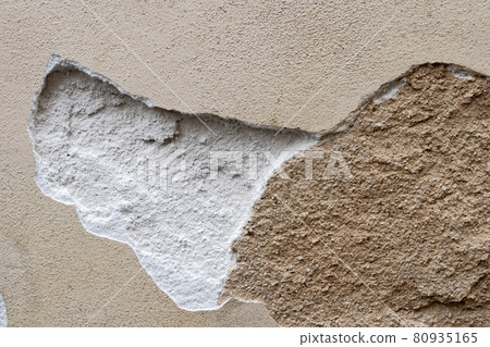 Destroyed weathered bonded plaster background. Texture of the old damaged wall with broken cracked plaster. 80935165