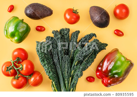 Black curly italian kale, tomatoes, avocado, pepper on orange background. Black curly italian kale, tomatoes, avocado, pepper on orange background. 80935595