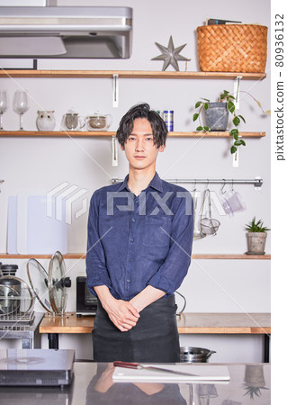站立在有圍裙的廚房裡的年輕人烹調男孩圖像 站立在有圍裙的廚房裡的年輕人烹調男孩圖像 80936132