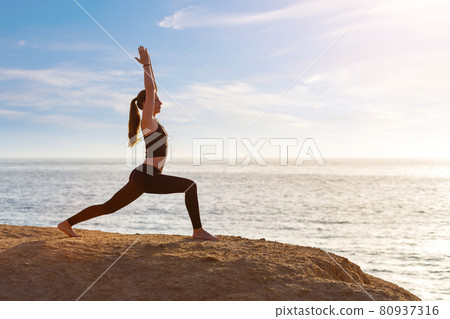 Young fitness woman practicing yoga at the seashore in the morning Young fitness woman practicing yoga at the seashore in the morning 80937316