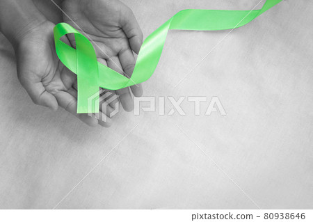 Hands holding emerald green or jade green ribbon on white fabric background with copy space, symbol for Liver Cancer awareness, World Cancer Day. Healthcare or hospital and insurance concept. Hands holding emerald green or jade green ribbon on white fabric background with copy space, symbol for Liver Cancer awareness, World Cancer Day. Healthcare or hospital and insurance concept. 80938646
