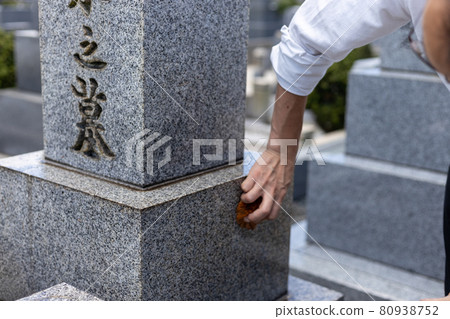 A man cleaning a grave with a scrubbing brush who came to visit the grave 80938752