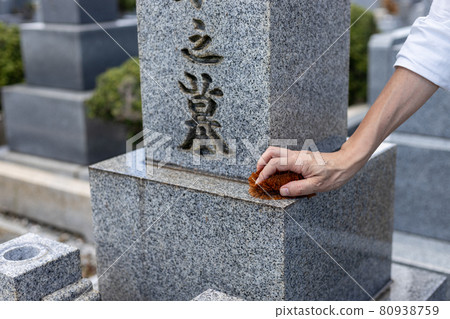 一個來掃墓的人用刷子清理墳墓 一個來掃墓的人用刷子清理墳墓 80938759