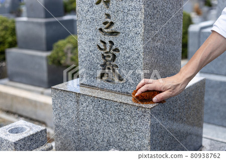 一個來掃墓的人用刷子清理墳墓 一個來掃墓的人用刷子清理墳墓 80938762