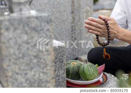 A man visiting a grave and holding hands 80939170