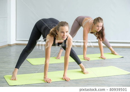 Two Caucasian women exercise doing the yoga pose stretching at home, healthy lifestyle concept Two Caucasian women exercise doing the yoga pose stretching at home, healthy lifestyle concept 80939501