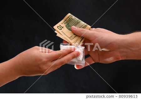 Drug dealer passes a dose to a merchant, sachets of powder on a black background. Drug dealer passes a dose to a merchant, sachets of powder on a black background. 80939613