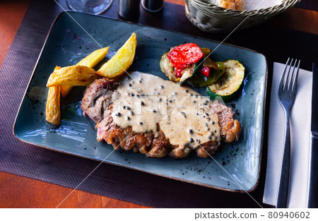 Veal steak with piquant creamy sauce, potatoes and vegetables 80940602