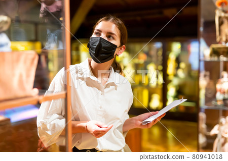 Woman exploring artworks in glass case in museum 80941018
