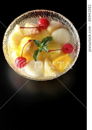 A bird's-eye view of a fruit punch containing various fruits and white balls on a black background 80941081