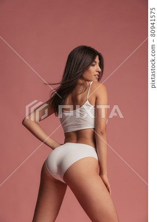 Back view of sportive body of young caucasian woman isolated on pink studio background. Natural beauty concept Back view of sportive body of young caucasian woman isolated on pink studio background. Natural beauty concept 80941575