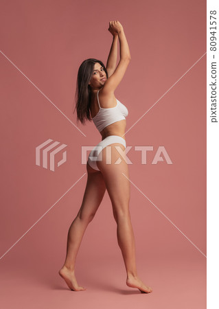 Portrait of young beautiful slim woman in lingerie posing isolated over pink studio background. Natural beauty concept. 80941578