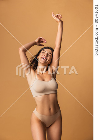 Portrait of young beautiful slim woman in lingerie posing isolated over brown studio background. Natural beauty concept. Portrait of young beautiful slim woman in lingerie posing isolated over brown studio background. Natural beauty concept. 80941601
