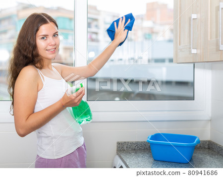 Portrait of young beautiful woman washing windows 80941686