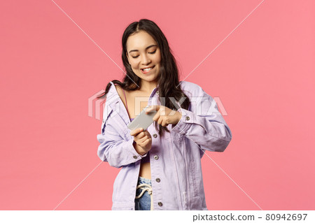 Online lifestyle, people and beauty concept. Portrait of stylish attractive young korean girl using mobile phone, eager to win and pass level in arcade, tilt smartphone as playing excting game 80942697