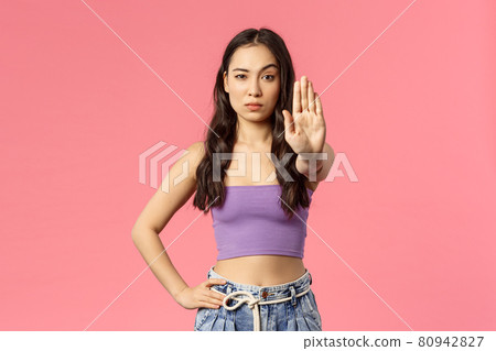 Waist-up portrait of confident stylish young woman stand in no trespassing pose, raise hand in stop sign, look camera skeptical, disagree, dont permit step closer, warning, pink background Waist-up portrait of confident stylish young woman stand in no trespassing pose, raise hand in stop sign, look camera skeptical, disagree, dont permit step closer, warning, pink background 80942827