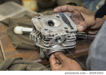 The mechanic repair the motorcycle  cylinder head. 80943083