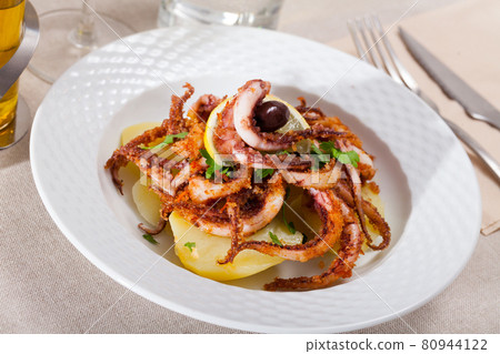 Delicious cooked squid or octopus tentacles with lemon and parsley on a plate Delicious cooked squid or octopus tentacles with lemon and parsley on a plate 80944122