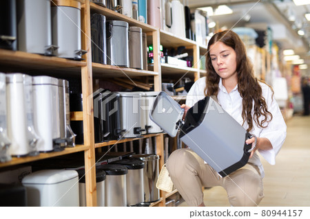 Woman choosing new trash bin at store Woman choosing new trash bin at store 80944157