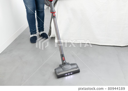 Woman cleaning with a cordless vacuum cleaner in a modern bedroom. Copy space 80944189