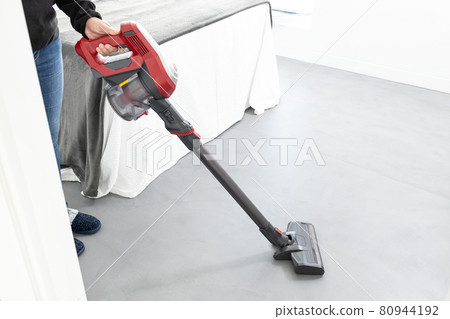 Woman working with a cordless vacuum cleaner in the modern bedroom of the house Woman working with a cordless vacuum cleaner in the modern bedroom of the house 80944192