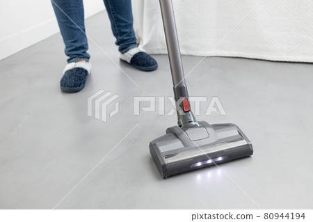 Woman cleaning with a cordless vacuum cleaner in a modern bedroom. Copy space 80944194