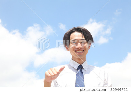 The upper body of a young smiling man holding a hand with the blue sky 80944721