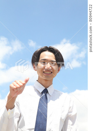 The upper body of a young smiling man giving a hand sign of blue sky and Good Jobs 80944722