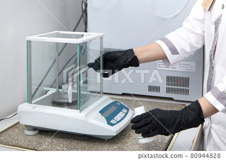 Scientist weighing chemicals by digital scales in grams in chemical laboratory Scientist weighing chemicals by digital scales in grams in chemical laboratory 80944828