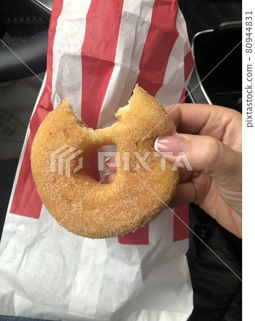 Bitten doughnut and paper bag. eating in a car. Fast food concept Bitten doughnut and paper bag. eating in a car. Fast food concept 80944831