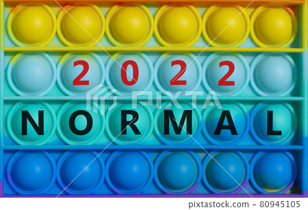 Symbol of covid-19 normal in 2022. Words 'Normal 2022' on rainbow Pop It. Beautiful background, copy space. Medical, covid-19 normal in 2022 concept. Symbol of covid-19 normal in 2022. Words 'Normal 2022' on rainbow Pop It. Beautiful background, copy space. Medical, covid-19 normal in 2022 concept. 80945105