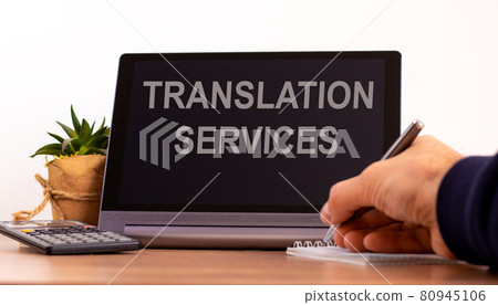 Education concept. Tablet with text 'translation services'. Male hand with pen, calculator, copy space. Education concept. Tablet with text 'translation services'. Male hand with pen, calculator, copy space. 80945106