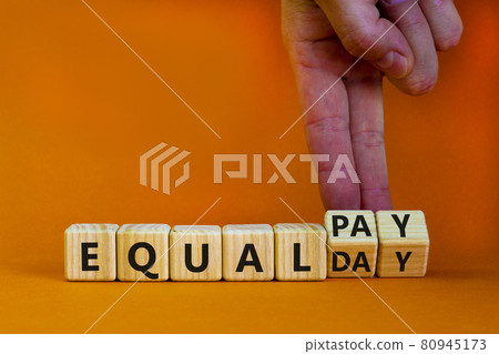 Equal pay day symbol. Businessman turns wooden cubes and changes words equal pay to equal day. Beautiful orange background. Copy space. Business and equal pay day concept. Equal pay day symbol. Businessman turns wooden cubes and changes words equal pay to equal day. Beautiful orange background. Copy space. Business and equal pay day concept. 80945173