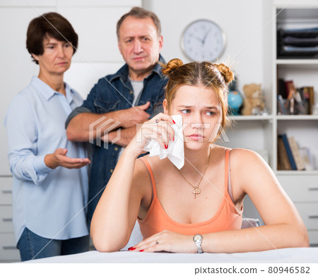 Parents are sympathying their sad daughter who is sitting at the table Parents are sympathying their sad daughter who is sitting at the table 80946582