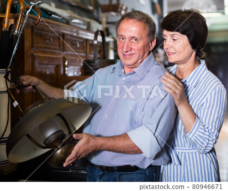 smiling mature couple is shopping the old lamp in the antique store smiling mature couple is shopping the old lamp in the antique store 80946671
