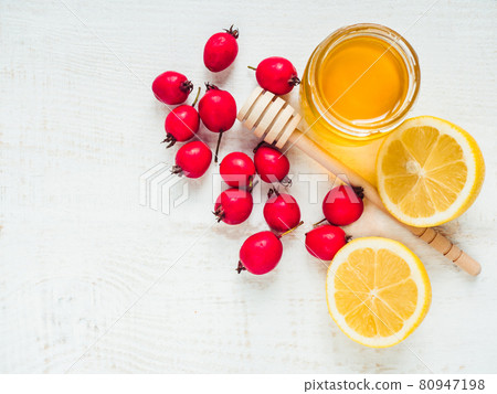 Fresh yellow lemon, jug of honey and red berries Fresh yellow lemon, jug of honey and red berries 80947198
