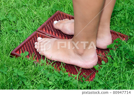 feet of a woman standing on a sadhu yoga board with nails 80947714