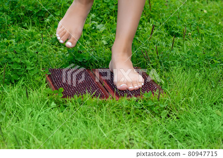 feet of a woman standing on a sadhu yoga board with nails 80947715