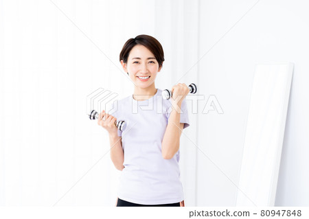 Middle-aged woman doing muscle training with dumbbells Middle-aged woman doing muscle training with dumbbells 80947848