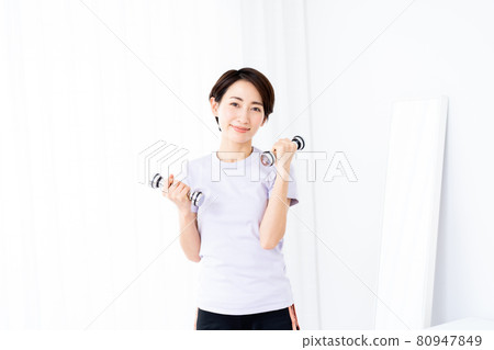 Middle-aged woman doing muscle training with dumbbells 80947849