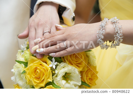 The bride and groom are stacking their left hands on the bouquet The bride and groom are stacking their left hands on the bouquet 80948622